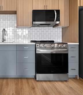 A modern kitchen with a stainless steel refrigerator, oven, and cabinets.