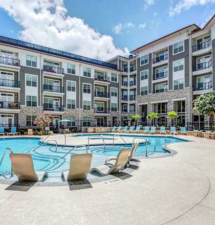 a swimming pool with an apartment building in the background at The Tribute in Raleigh, North Carolina