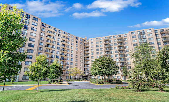 a view of a large apartment complex with grass and trees