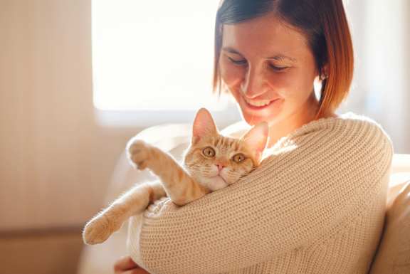 A woman is holding a cat in her arms.at The Residences at The Gilmore in Gilbert, AZ