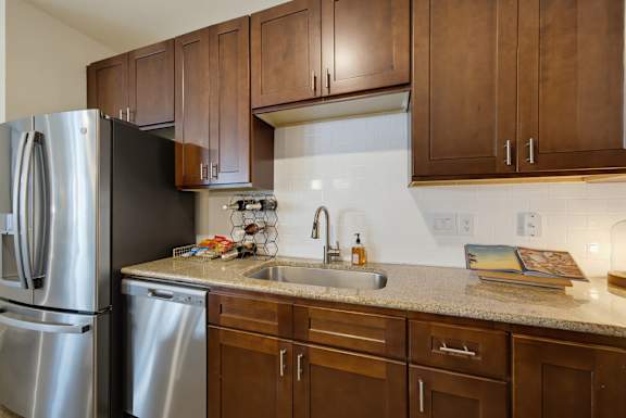 Kitchen counter with an undermount sink, gooseneck faucet, white subway tile backsplash, and a stainless dishwasher.