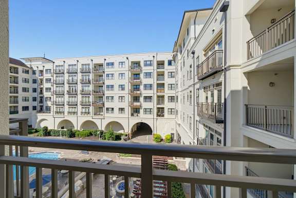 View from a private balcony over the courtyard, with the pool below and balconies across the facing building wing.