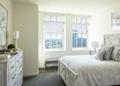 Thumbnail 2 of 9 - A bedroom with a large bed and a dresser with a plant on top at Residences Providence, Providence, Rhode Island