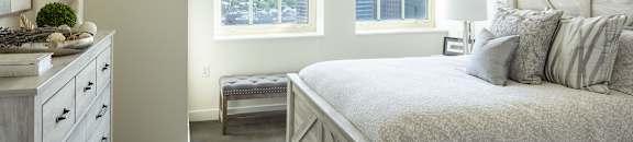 A bedroom with a large bed and a dresser with a plant on top at Residences Providence, Providence, Rhode Island