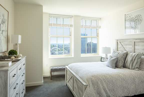 A bedroom with a large bed and a dresser with a plant on top at Residences Providence, Providence, Rhode Island