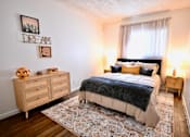 Thumbnail 6 of 8 - A bedroom with a bed, nightstands, and a rug.