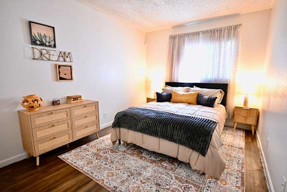 A bedroom with a bed, nightstands, and a rug.