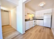 Thumbnail 8 of 8 - A kitchen with white appliances and wooden floors.