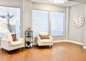 Thumbnail 5 of 8 - Two white chairs are placed in a room with a clock on the wall.