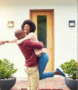 a man holding a woman in front of a house