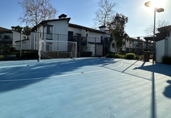 a tennis court in front of some apartments on a sunny day at The Bryant Apartments at Yorba Linda, Yorba Linda