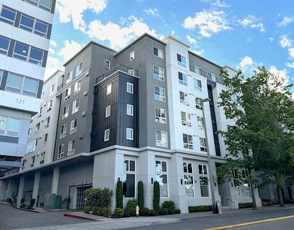 A modern multi-story building with a mix of white and dark grey balconies.