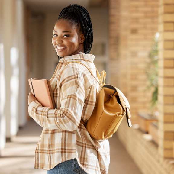 portrait of a smiling young woman holding books and cell phone at Creekview Homes, California, 95928