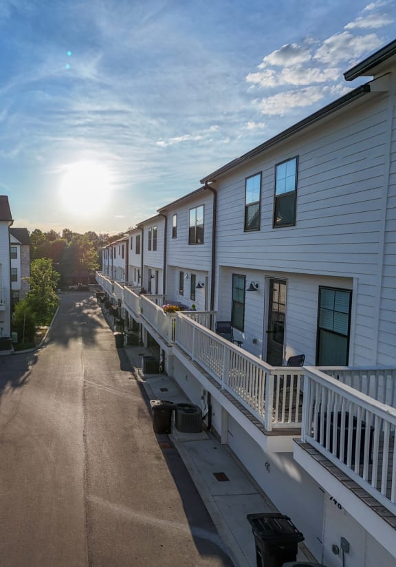 the sun sets over a street between rows of houses