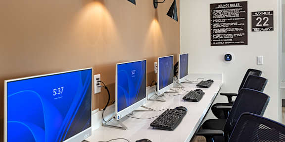 A row of computers are lined up on a white desk.