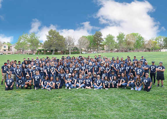 A group of people wearing blue shirts with the letter "P" on them are posing for a photo.