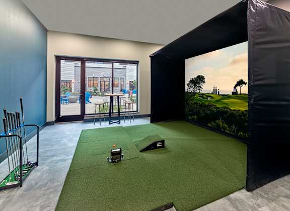 A room with a golf simulator and a view of a golf course at Cityplace Apartment Homes Apartments, Allentown, PA, 18101