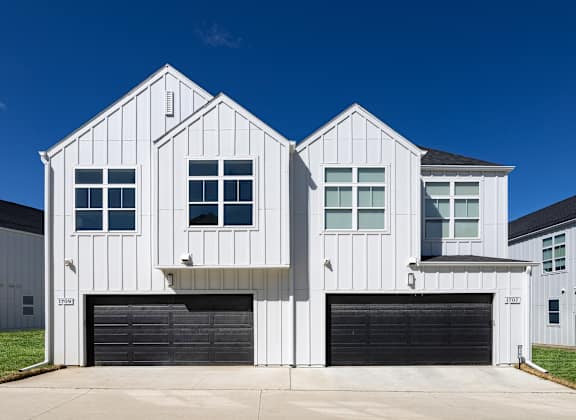 A white two story house with a black garage door.