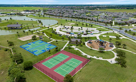 A tennis court is surrounded by a fence and a grassy area.