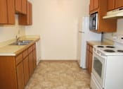 Thumbnail 5 of 8 - A kitchen with white appliances and wooden cabinets.