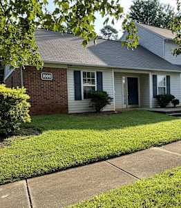 A house with a blue door and windows is surrounded by green grass.