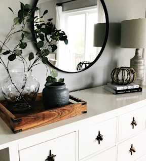 A white dresser with a wooden tray on top holding a vase and a pot.