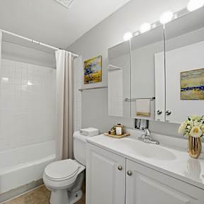 A white bathroom with a toilet, sink, and shower.