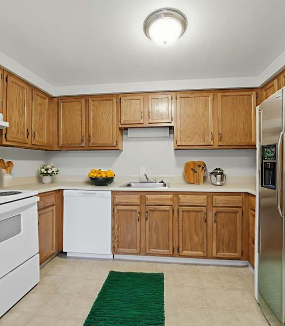A kitchen with wooden cabinets and a stainless steel refrigerator.