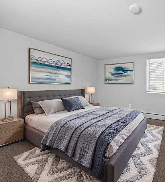 A bedroom with a large bed and a painting on the wall.