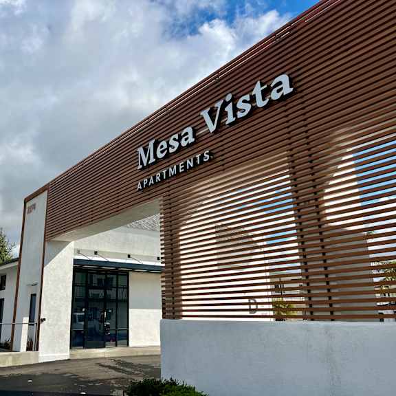 The front of the Mesa Vista Apartments building with a flag flying in the background.