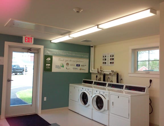 a laundry room with two washing machines and a door to a parking lot