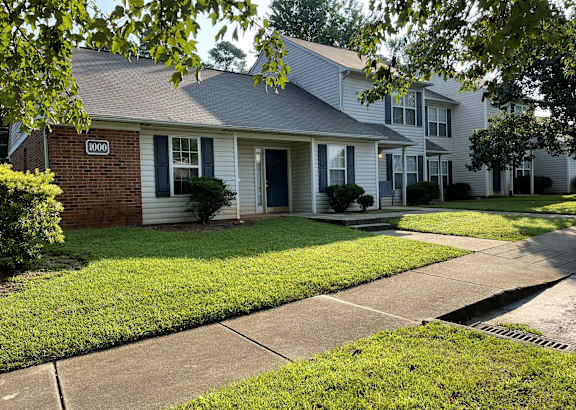 A house with a blue door and windows is surrounded by green grass.