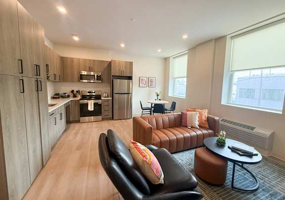 A modern living room with a kitchen in the background.