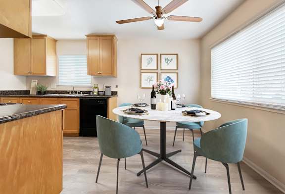 A kitchen with a table set for two and a ceiling fan.