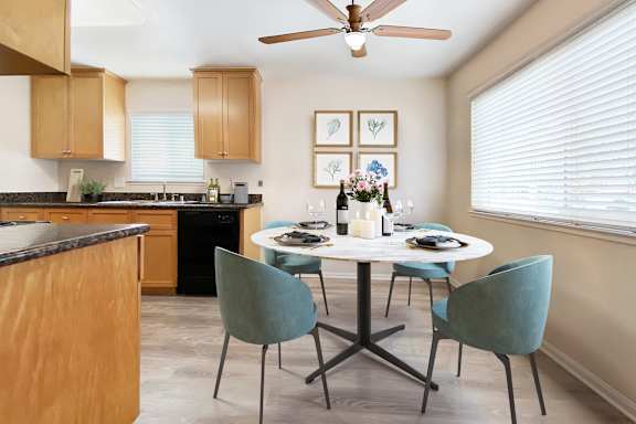 A kitchen with a table set for two and a ceiling fan.
