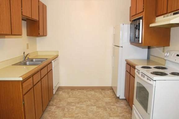 A kitchen with white appliances and wooden cabinets.