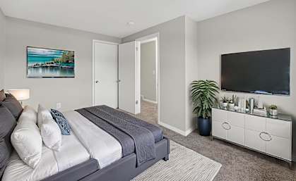 A bedroom with a bed, a dresser, and a painting on the wall.