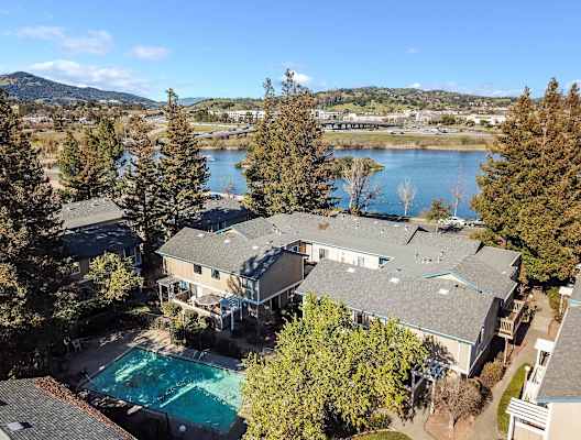 aerial view of apartment buildings, pool, and lake