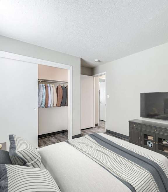 A bedroom with a bed, a wardrobe, and a television at The Ridges Apartments, Des Moines, Iowa
