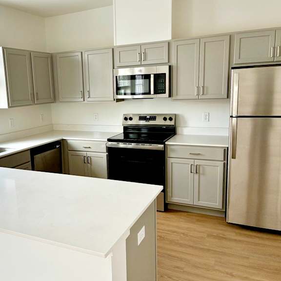 A kitchen with a white counter top and stainless steel appliances.
