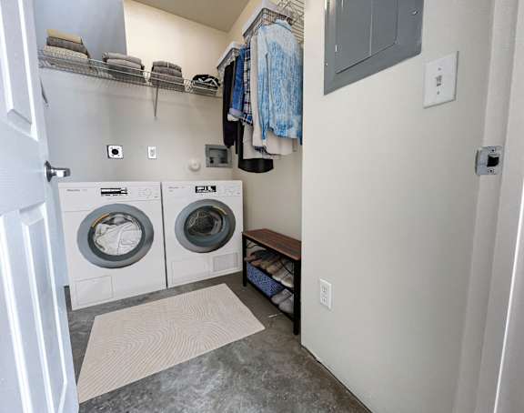 A laundry room with a washer and dryer and a bench.