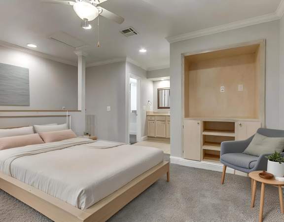 A bedroom with a large bed and a chair.