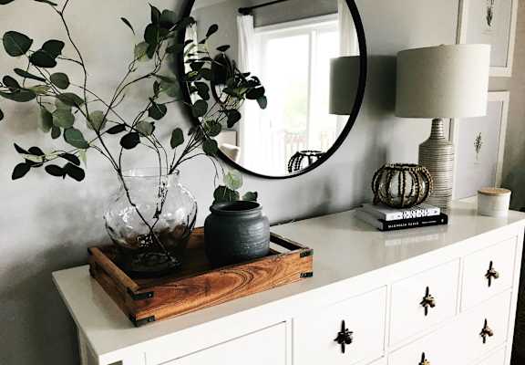 A white dresser with a wooden tray on top holding a vase and a pot.