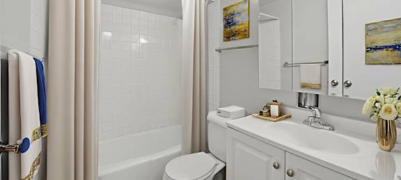 A white bathroom with a toilet, sink, and shower.
