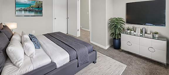 A bedroom with a bed, a dresser, and a painting on the wall.