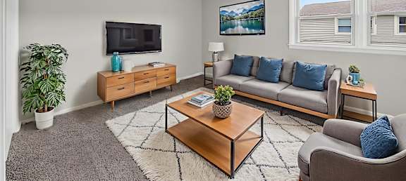 A living room with a grey couch, a wooden coffee table, and a flat screen TV.