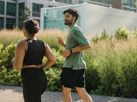 A man and a woman are jogging in a park.at Chalkwood Apartments, Ebbsfleet Valley, DA10 1HQ