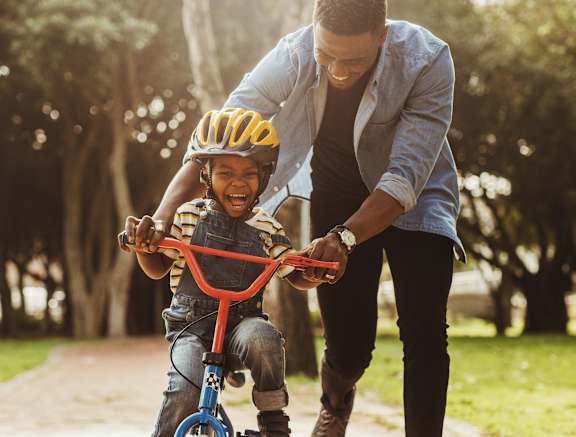 A man is teaching a young boy how to ride a bike at Woodland Place Apartments, Langford, BC