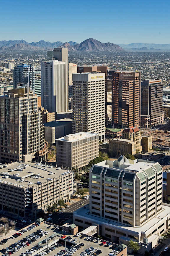 A cityscape with a variety of buildings and a mountain range in the background.