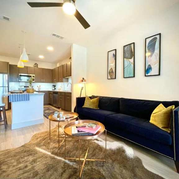 A modern living room with a blue couch and a kitchen area in the background.